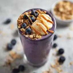 blueberry banana peanut butter smoothie in a tall glass