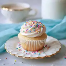 Frosted protein cupcake with sprinkles on white plate