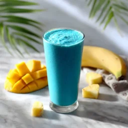 Blue spirulina smoothie in tall glass with tropical fruits