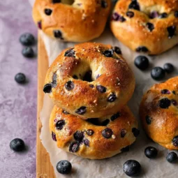 Freshly baked blueberry bagels stacked with juicy blueberries