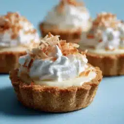 Delicious Coconut Cream Tartlets topped with coconut flakes and whipped cream
