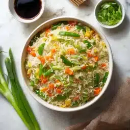 Bowl of flavorful vegetable fried rice with colorful vegetables and herbs
