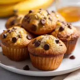 Freshly baked Greek Yogurt Banana Muffins on a wooden table.