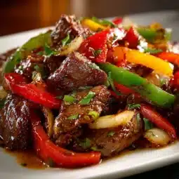 Delicious pepper steak served with peppers and spices on a plate.