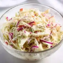Fresh fennel slaw topped with creamy yogurt-dill dressing in a bowl