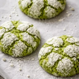 Freshly baked matcha crinkle cookies with a sugar coating and emerald green cracks.