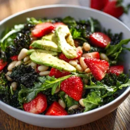 A vibrant roasted strawberry salad with greens, nuts, and feta cheese