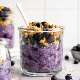 Glass jar of Blueberry Overnight Oatmeal topped with fresh blueberries and granola.