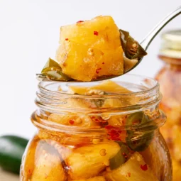 Jar of homemade Pineapple Cowboy Candy with pineapple chunks and jalapeños.